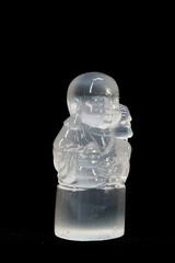 Antique Selenite Buddha sculpture isoated on black background. Selenite or Moon stone carving in Buddha shaped