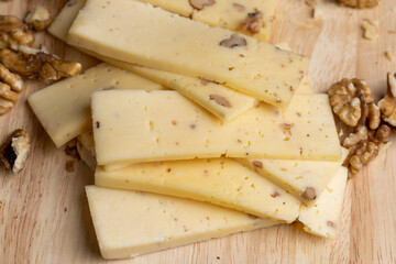 Sliced piece of milk cheese with walnuts