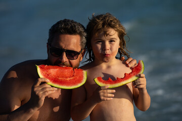 Father and son with watermelon on summer beach outdoor. Father and kid son having fun in summer day. Father and child son summer vacation and healthy eating. Father eats juicy watermelon on the beach.