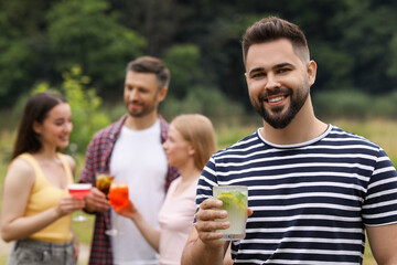 Friends having cocktail party outdoors. Happy man with glass of drink, selective focus