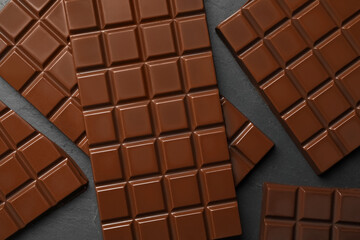 Pieces of tasty chocolate bars on grey table, flat lay