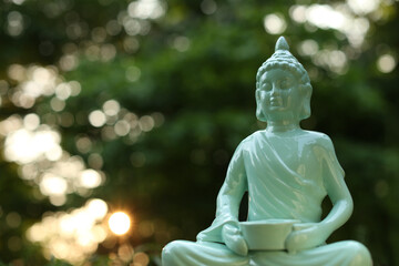 Decorative Buddha statue on blurred background outdoors. Space for text