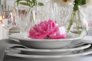 Stylish table setting with beautiful peony in dining room, closeup