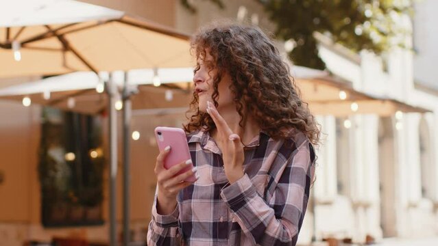 Oh my God Wow. Excited happy joyful winner pretty young woman use smartphone typing browsing celebrating win good message news. Girl with mobile phone walking in urban city sunshine street outdoors