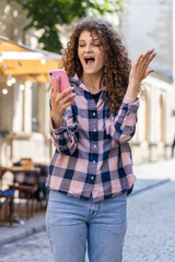 Young woman use mobile smartphone celebrating win good message news, lottery jackpot victory, giveaway online outdoors. Happy girl tourist walking in urban city street. Town lifestyles. Vertical