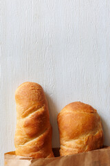Two loaf of handmade baguette Bread packed in paper on white wooden table. Close up, copy space. Top view, flat lay. Vertical