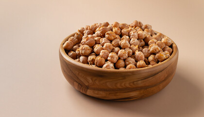 Roasted Chickpea or Leblebi in wooden bowl on beige background. Turkish snack. Selective focus, copy space.