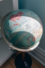 gros plan sur un globe terrestre sur pied à côté d'une fenêtre avec de la lumière naturelle