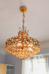 vue sur un luminaire en métal doré au plafond de forme ronde avec des cristaux intégrés