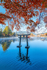 Yufuin, Japan - Nov 27 2022: Tenso-jinja shrine at lake Kinrin, is one of the representative sightseeing spots in the Yufuin area at the foot of Mount Yufu. - obrazy, fototapety, plakaty