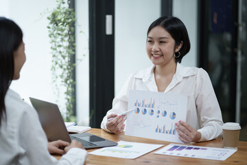 Beautiful Asian smart businesswoman discussing the project with her coworker, brainstorming the idea for the new projects.