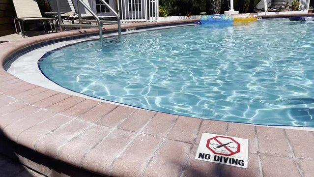 Clear blue pool at a resort patio furniture No diving sign sunny clear day