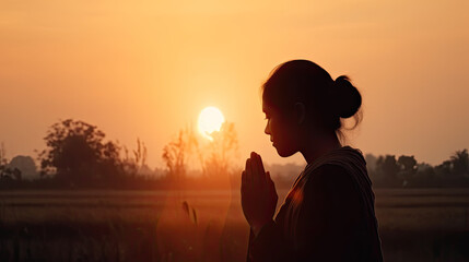 Silhouette off young woman praying for Gods blessing at sunset dawn
