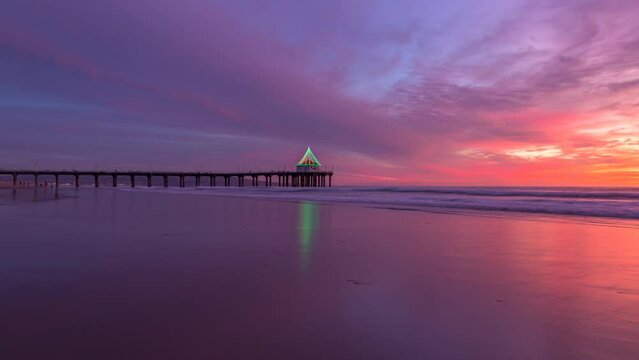 Vibrant sunset in Manhattan beach during winter. - timelapse. Low tide reflections as waves lap the shore.