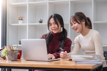 Two young female students tutoring and catching up workbook together