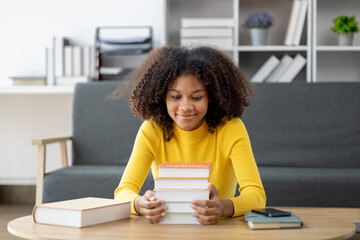 An American woman sits in the living room on weekends, with stacks of books, she is reading and studying for exams. Student concept, students reading, studying.