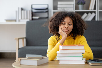 An American woman sits in the living room on weekends, with stacks of books, she is reading and studying for exams. Student concept, students reading, studying.