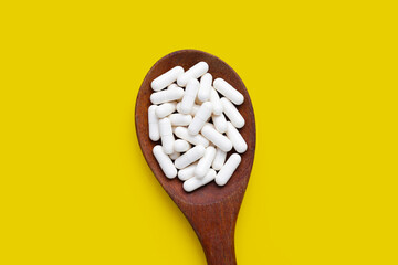 Medicine capsules on yellow background.