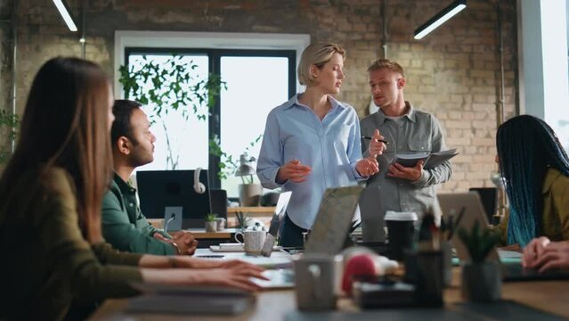 Woman ceo leading business meeting with young creative team in office boardroom.