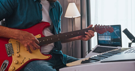 A musician recording electric guitar in digital studio at home. A composer is using modern equipment to help create a melody.