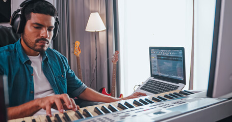 Asian musician is creating new music in his home studio. A composer is using modern equipment to help create a melody.