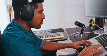 Asian musician is creating new music in his home studio. A composer is using modern equipment to help create a melody.