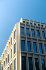 Modern office building exterior with glass facade on clear sky background. Transparent glass wall of office building with yellow decoration. Element of facade of modern European building Commercial