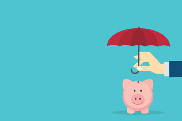 Hand holding small umbrella over piggy bank