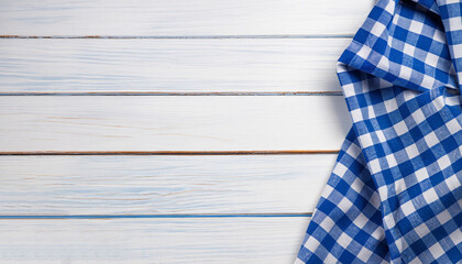 Blue checkered tablecloth textile on white wooden table background