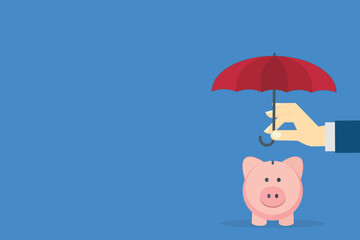 Hand holding small umbrella over piggy bank