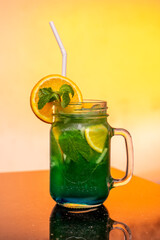 Glass of Green Color Cocktail with Orange Front View