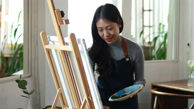 Asian woman painting on canvas, she is an artist who creates watercolor painting, art painting. Concept artist design drawing art on canvas paper.