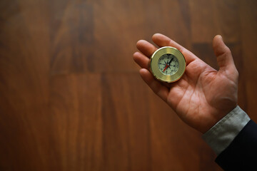 man in suit holding golden compass on gray background