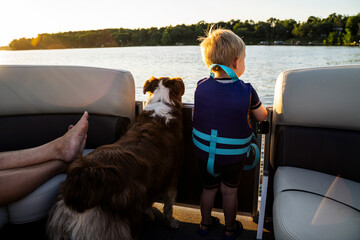 Blonde Toddler Boy Looking at Water on Boat with Family Dog - obrazy, fototapety, plakaty