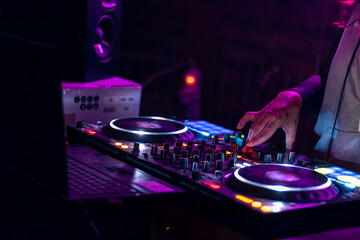 hands of dj playing at an electronic party with very colorful lighting