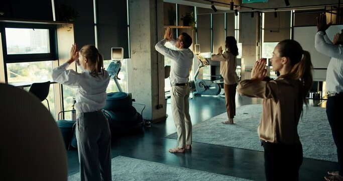 A group of business people are engaged in meditation, they stand near each other and put their hands together in the office