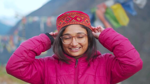 Portrait of beautiful smiling Indian girl wearing Himachali Cap standing at Himalayan mountains in background. Tourist enjoying holidays in mountains at Lahaul, Himachal Pradesh, India.