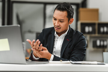 Close-up of Asian Indian businessman wrist pain from using computer Office Syndrome, hand pain from occupational disease, hardworking