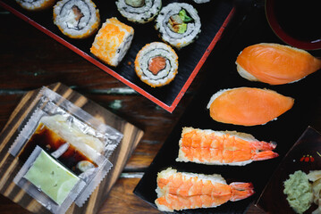 Sushi Set nigiri shrimp and salmon and sushi california rolls with avocado and maki with carrot, on wood,top view