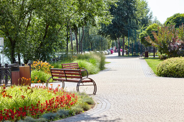 Rest area with bench surrounded by blooming flowers and ornamental shrubs in Kyiv, Europe. Place to...