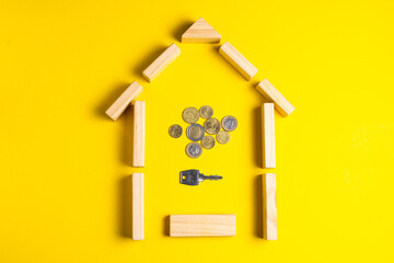 Fototapeta na wymiar Wooden house model with coins, money, copy space on yellow background.