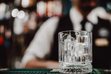 Ice cube in an empty glass on a bar counter in bar or pub
