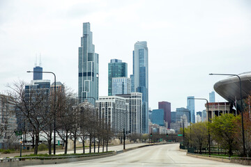 Chicago Illinois USA. Driving on empty urban street, skyscraper, traffic light, tree, cloudy sky.