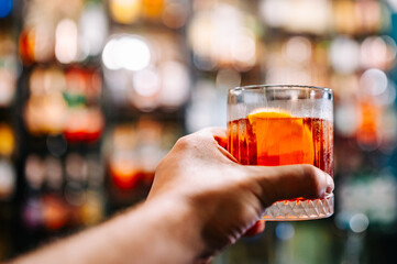 man hand hold glass red coktail in bar