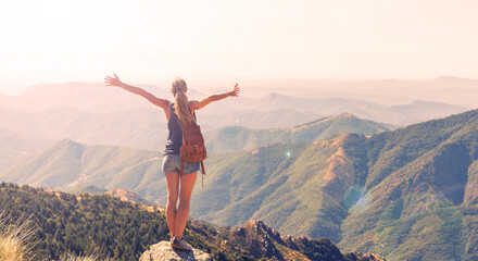Hiker woman standing on peak enjoying panoramic view of mountain range ( Mont aigoual in France)-...
