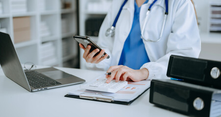 Healthcare costs and fees concept.Hand of smart doctor used a calculator and smartphone, tablet for...