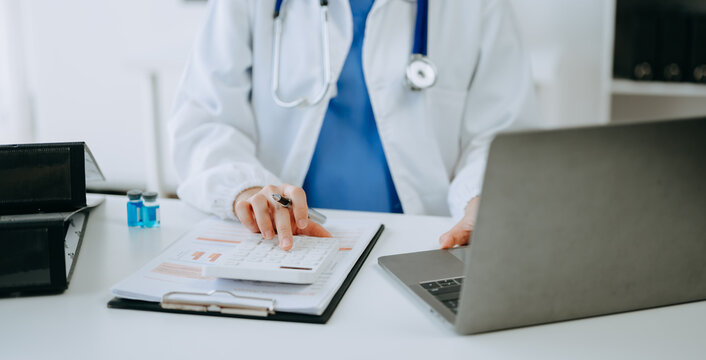 Healthcare costs and fees concept.Hand of smart doctor used a calculator and smartphone, tablet for medical costs at hospital