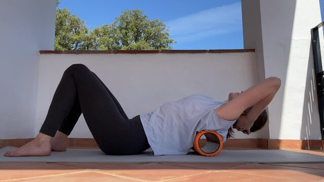Woman doing back muscles myofascial release with foam roller for back pain relief