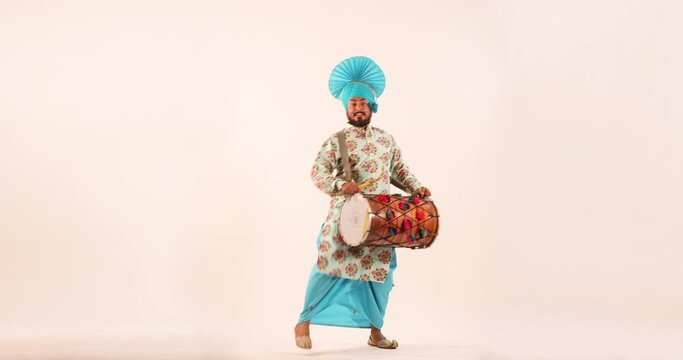 Sikh man doing bhangra dance with drum during Baisakhi celebration