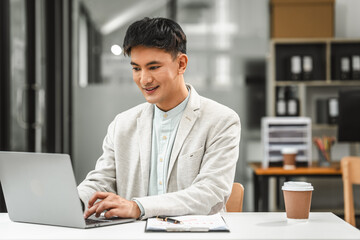 Obraz premium Working on laptop pc, Asian business asian man supervisor analyse financial report of responsible worker pay attention on mistakes propose correction.